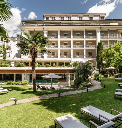 Wunderschöner und stilvoll gepflegter Garten mit Hinteransicht vom Hotel Meranerhof