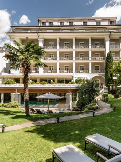 Wunderschöner und stilvoll gepflegter Garten mit Hinteransicht vom Hotel Meranerhof